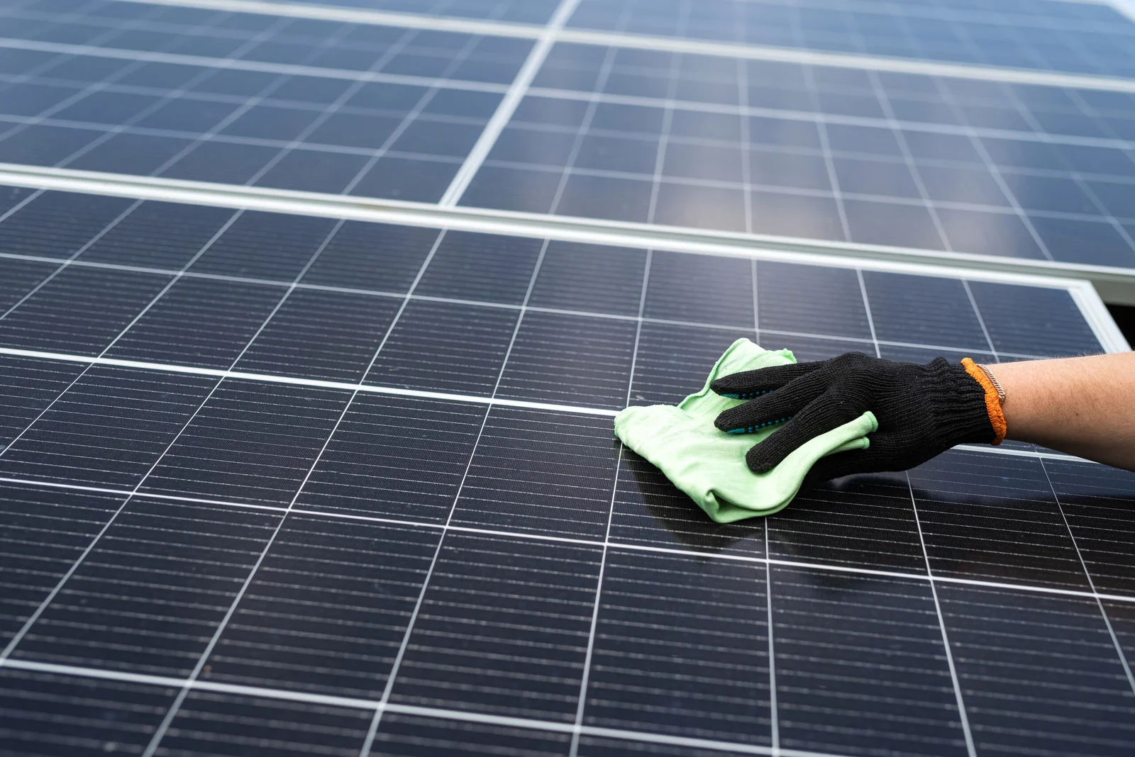 male-hand-cleaning-solar-panels-with-towel-wipe-dirty-solar-power-green-energy-scaled